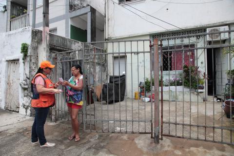 técnica da defesa civil entrega panfleto a mulher #pracegover 