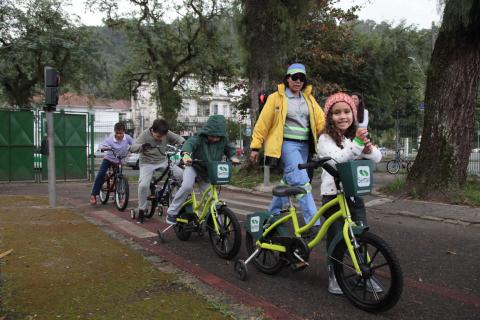 agente ajuda crianças a andar de bicicletas pela pista #pracegover 