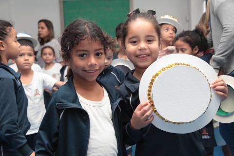 menina segura chapéu ao lado de amiga #pracegover 