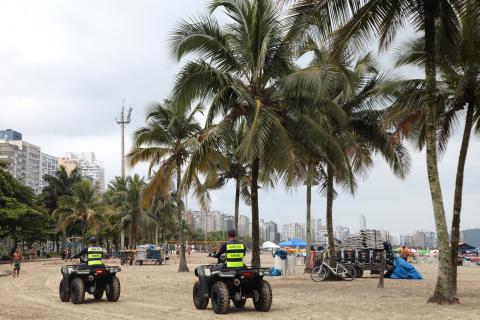 Guardas municipais percorrem a orla em triciclos. Ao lado direito aparecem palmeiras. #Pracegover
