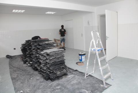 peças do piso empilhadas em sala com novo piso já colocado #pracegover 