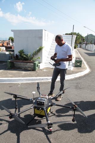 homem opera controle na frente de drone ao chão #pracegover 