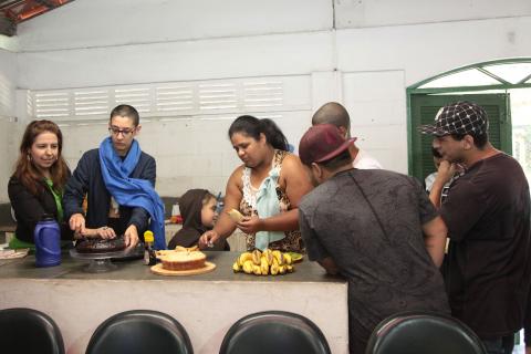 alunos cortam pedaços de doces na mesa #pracegover 