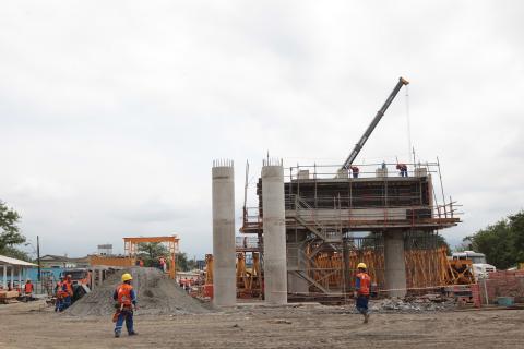 homens passando ao lado de viaduto em obras #pracegover 