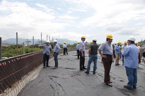 Homens estão em pé sobre a estrutura de um viaduto em construção