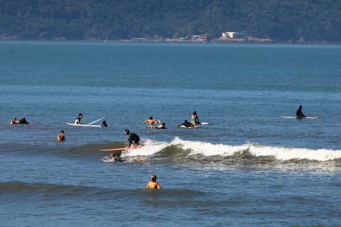 Surfistas aproveitam as ondas e dia de sol na praia do José Menino. #pracegover