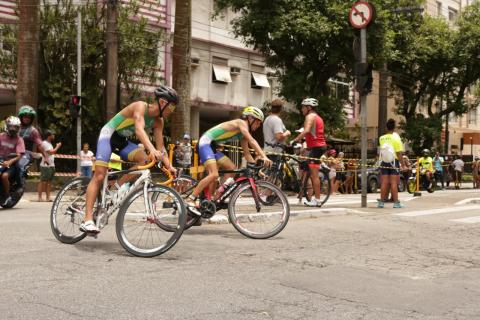 Atletas fazem curva montados em suas bicicletas. #pracegover