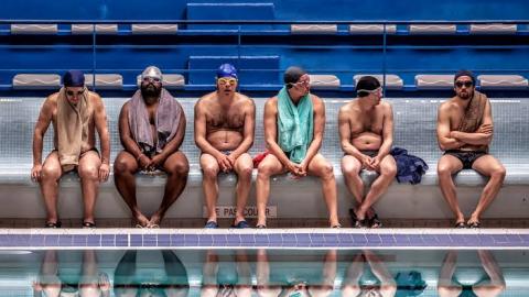 homens sentados na beira de piscina em cena de um banho de vida #pracegover 