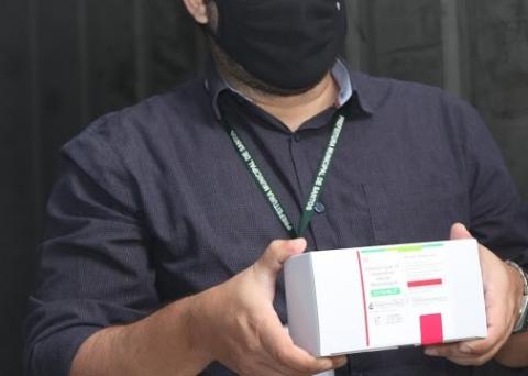 Técnico da Prefeitura segura caixa com vacina. #pracegover