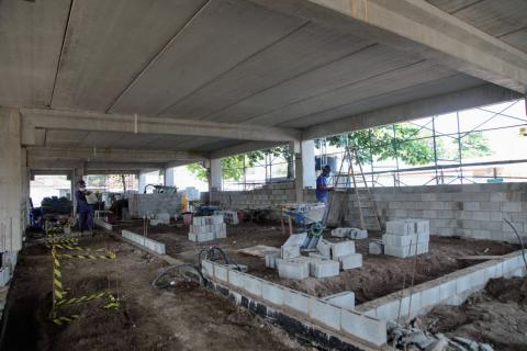 Construção de alvenaria na área interna. Há homens trabalhando. #Paratodosverem