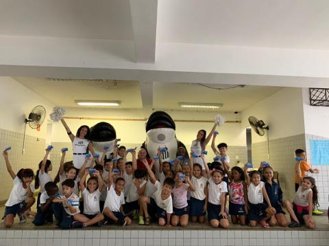 Cerca de trinta crianças posam para foto com mascotes em formato de baleia