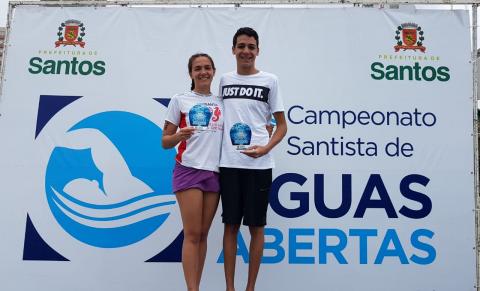 Sobre o pódio, Julia Pereira e Gabriel Cruz exibem troféus