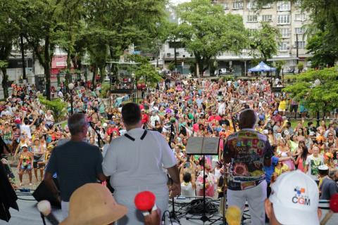 #pracegover Banda se apresenta no palco à frente de milhares de pessoas fantasiadas na praça