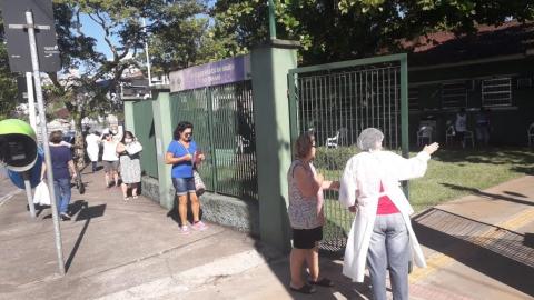 idosa é orientada por profissional de saúde na porta de unidade #paratodosverem