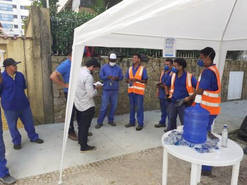 operários na frente de tenda com água e alcool em gel #paratodosverem