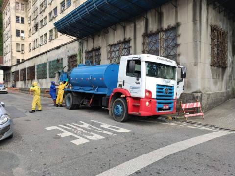 caminhão da limpeza parado em rua com 2 operários ao lado #paratodosverem