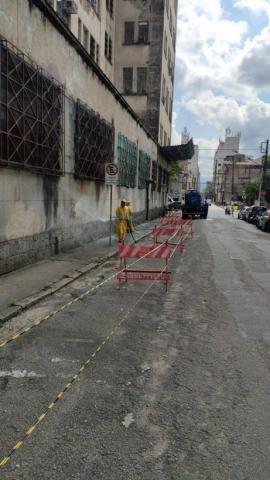 Homem está apontando jato d'água para a calçada. #Paratodosverem