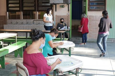 funcionários em mesa aguardam familiares de alunos #paratodosverem 