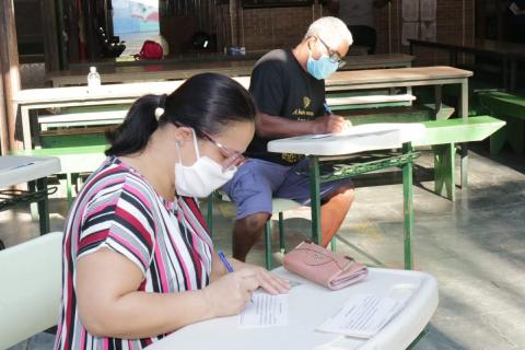 funcionários em mesa aguardam familiares de alunos #paratodosverem 