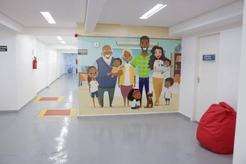 sala onde há uma parede pintada com uma familia #paratodosverem