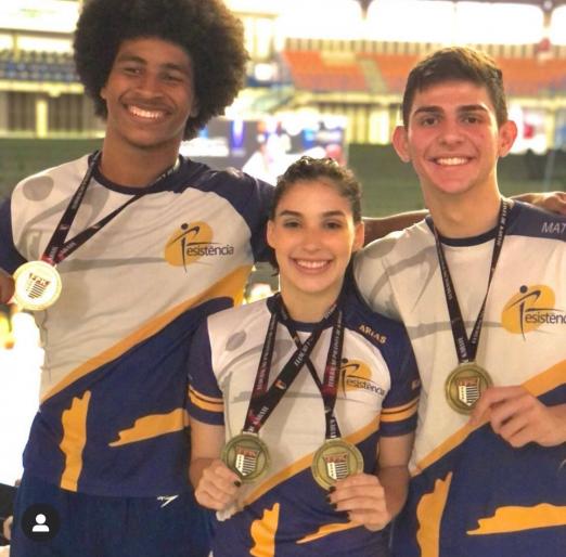 tres jovens exibem medalhas #paratodosverem