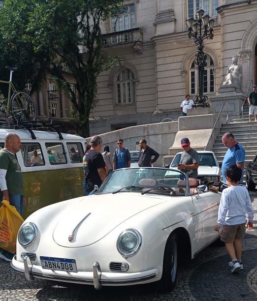 carro antigo está em exposição na praça. publico está admirando. #paratodosverem