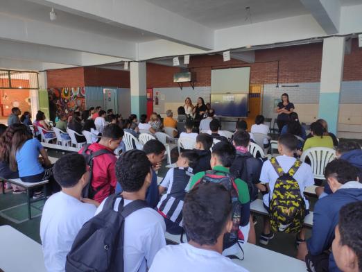 alunos sentados ouvindo apresentação #paratodosverem 