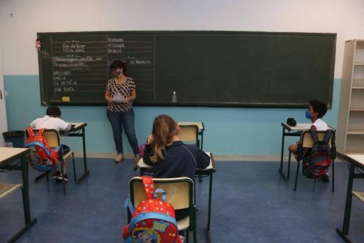 professora na sala de aula com alunos sentados na mesa #paratodosverem 