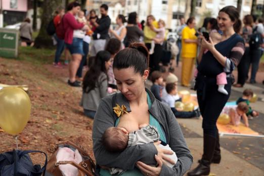 Mulher está amamentando em um parque. #Paratodosverem