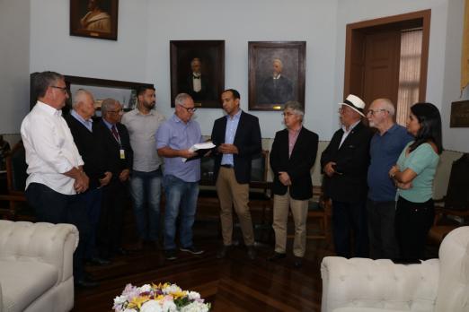 Prefeito entrega documento ao presidente da Câmara. Vários vereadores estão presentes e lado a lado na foto. #Pracegover