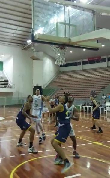 quatro atletas, dois de santos e dois de outro time estão no garragão da quadra, olhando para cima. A bola está na direção da cesta. #paratodosverem