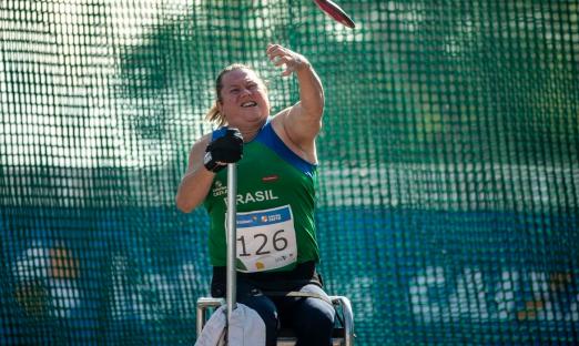 paratleta Beth Gomes está sentada na cadeira e lança disco. #paratodosverem