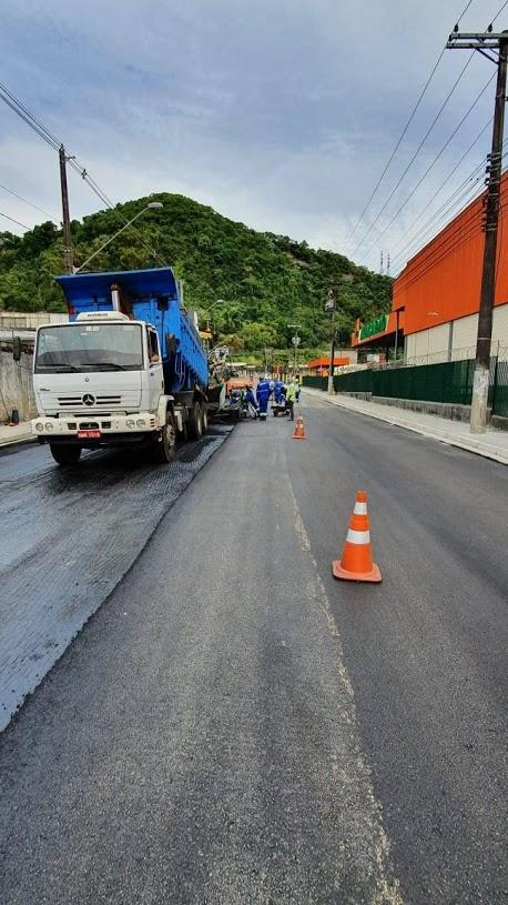 Caminhão que aplica massa asfáltica está na pista. Outro trecho está bloqueado. 