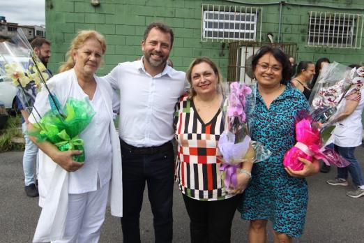 homenageadas posam com flores e secretário #paratodosverem