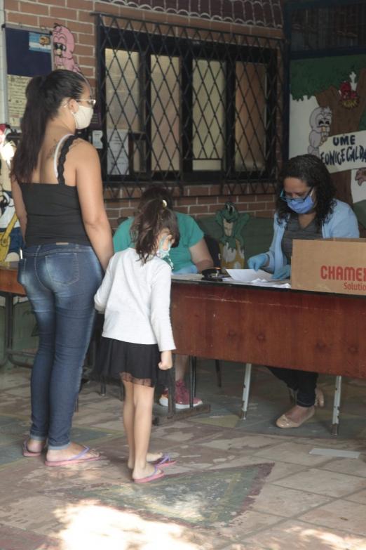 Mulher e criança estão à frente de uma mesa sendo atendidas. #Paratodoverem