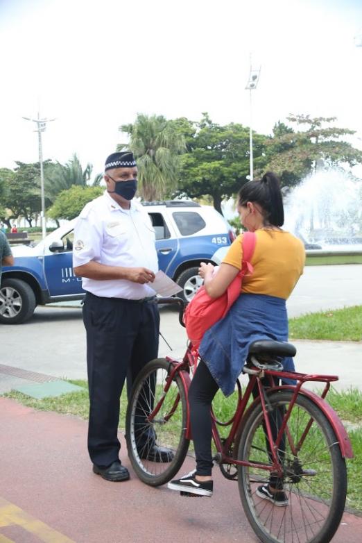 Agente da Guarda Municipal está diante de ciclista sem máscara. #Paratodosverem