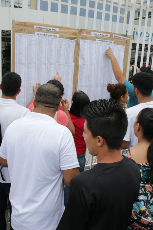 Candidatos procuram nomes nas listas afixadas no portão. #pracegover