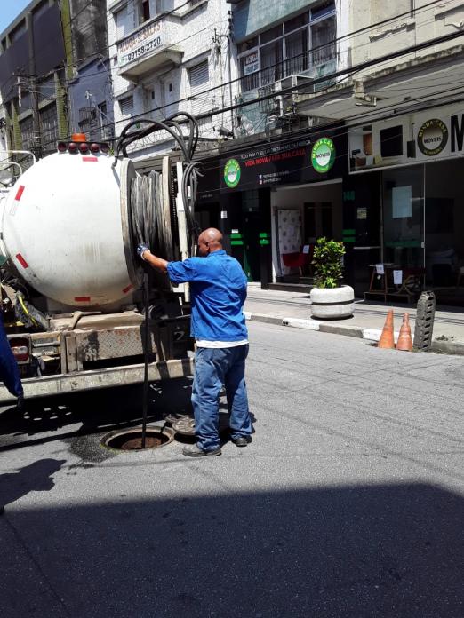 Homem opera equipamento de hidrojateamento de caminhão em galeria na rua. #pratodosverem