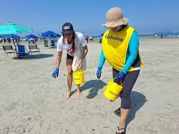 duas pessoas recolhendo lixo na praia #paratodosverem