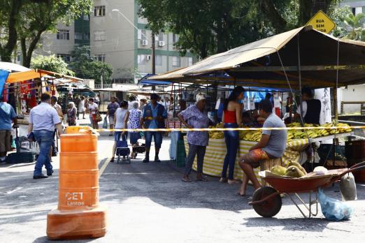 Feira livre armada em rua, com cone delimitando o acesso