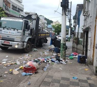 caminhão está parado em rua. Há muito lixo no chão em torno do imóvel. #paratodosverem