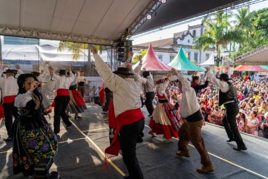 pessoas dançando com roupas típicas em palco #paratodosverem