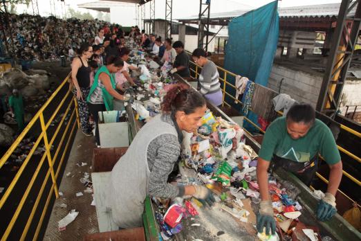 Linha de reciclagem com catadores fazendo a separação #pracegover. 