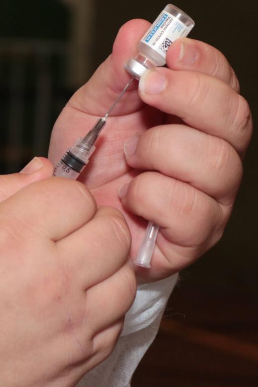 #pracegover enfermeiro insere agulha de seringa em frasco de vacina