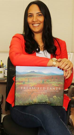 Sandra está sentada com um livro à frente do corpo. #paratodosverem