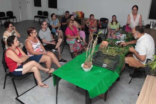 professor fala a alunas com flores em mesa na frente #paratodosverem