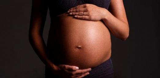 imagem em close de barriga de gestante com as mãos da mulher, uma abaixo e outra acima da barriga. #paratodosverem