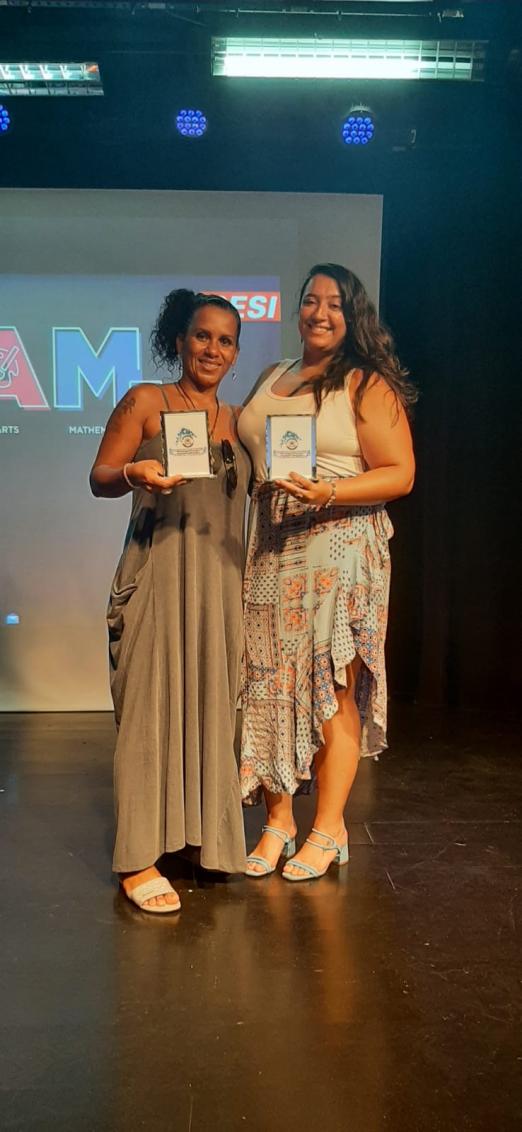 Glaucia e Deise posam para foto com troféus nas mãos. #paratodosverem