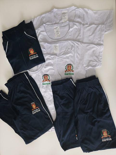 kit de uniforme com camisetas, bermuda e short saia sobre uma mesa. #paratodosverem 