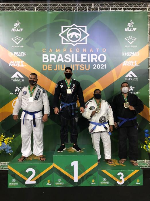 Atletas com quimono no pódio com medalhas #paratodosverem